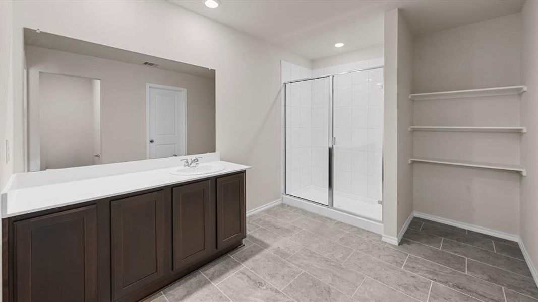 Bathroom featuring a dark wood-finish vanity with a white countertop and undermount sink, a large wall-mounted mirror, and a glass-enclosed shower with white tiled walls Bathroom featuring a dark wood-finish vanity with a white countertop and undermount sink, a large wall-mounted mirror, and a glass-enclosed shower with white tiled walls