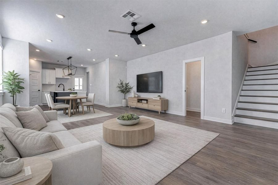 From this angle, you’ll appreciate the home’s main level flow where the kitchen, living, and stairwell connect with thoughtful functionality. Recessed lighting, fresh white walls, and warm-toned flooring give you a blank canvas ready for life and style. This photo has been virtually staged for visual reference.