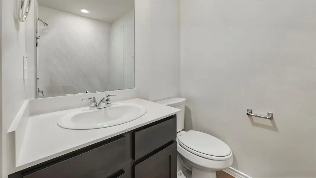 Bathroom vanity featuring a white countertop with an integrated sink, chrome faucet, and dark wood-finish cabinetry