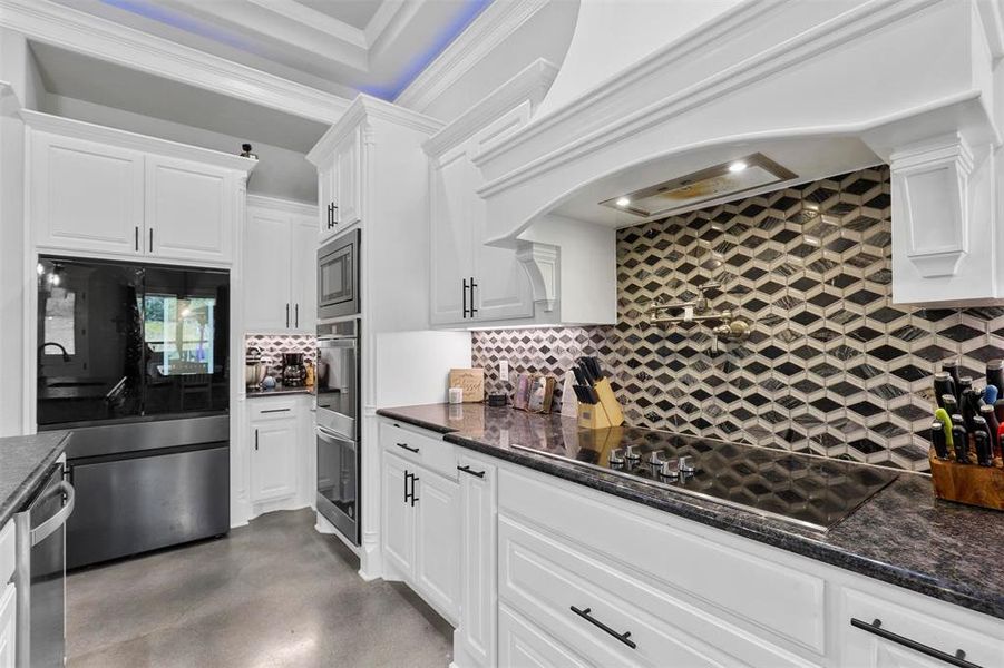 Kitchen featuring premium range hood, white cabinets, and black appliances