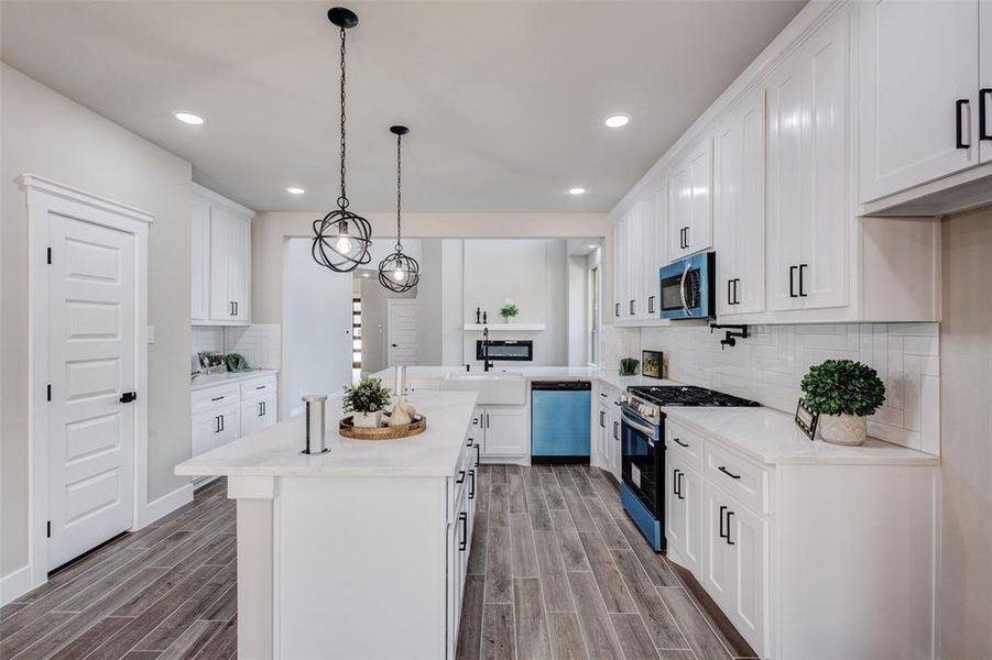 Kitchen with decorative backsplash and lighting, stainless steel appliances, wood-style tile flooring, and recessed lighting