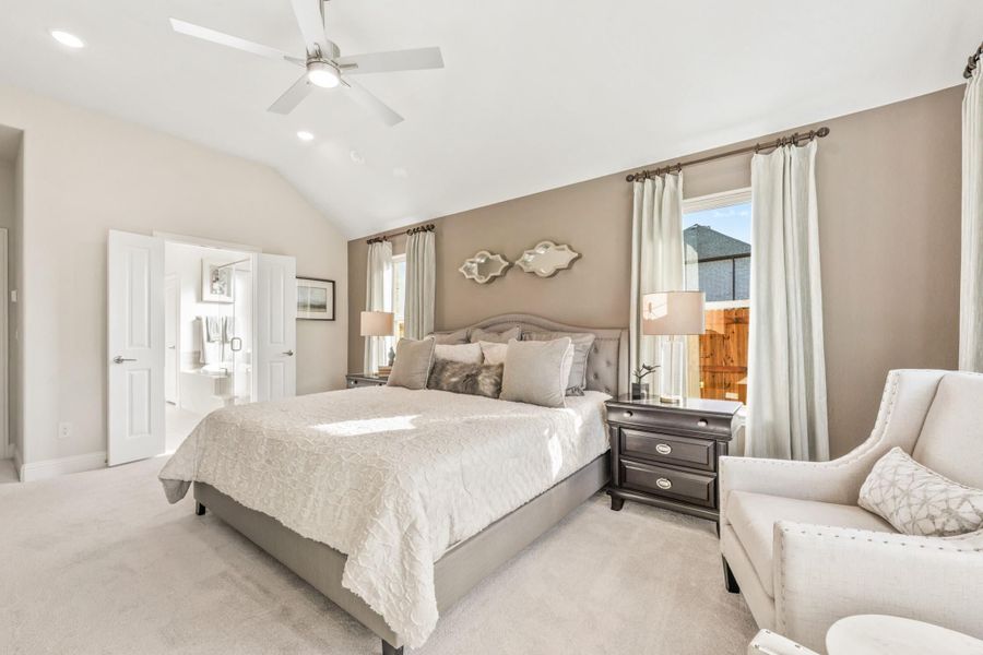 Master bedroom with vaulted ceiling, ceiling fan, king bed, and ensuite bathroom access Master bedroom with vaulted ceiling, ceiling fan, king bed, and ensuite bathroom access