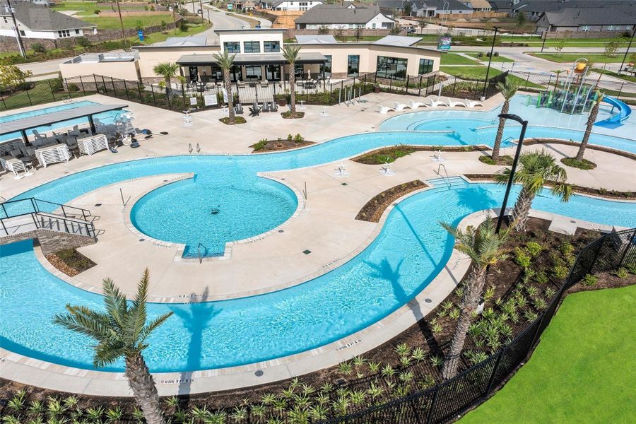 A winding lazy river snakes through the amenity village — palm-flanked curves, shallow water, and lounge platforms invite a slow, sunlit float.