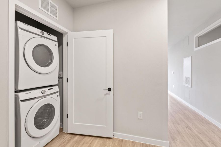 Laundry room featuring light wood-style floors and stacked washer and clothes dryer