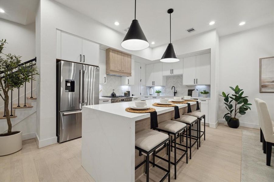 This kitchen boasts a premier Bosch appliance package with refrigerator included, wine refrigerator, quartz countertops, island with waterfall, stainless steel sink and fabulous designer pendant lighting!