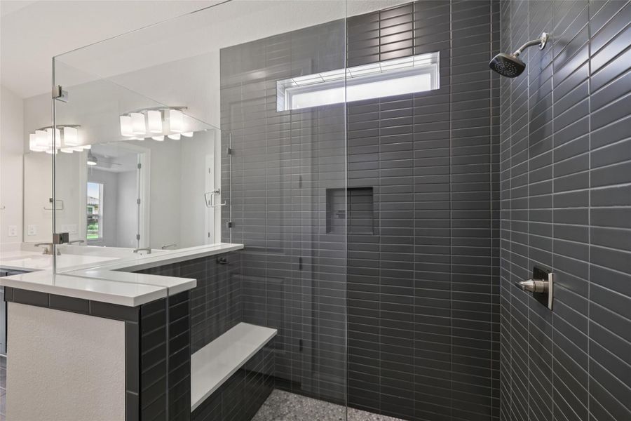 Full bath featuring tiled shower and double vanity