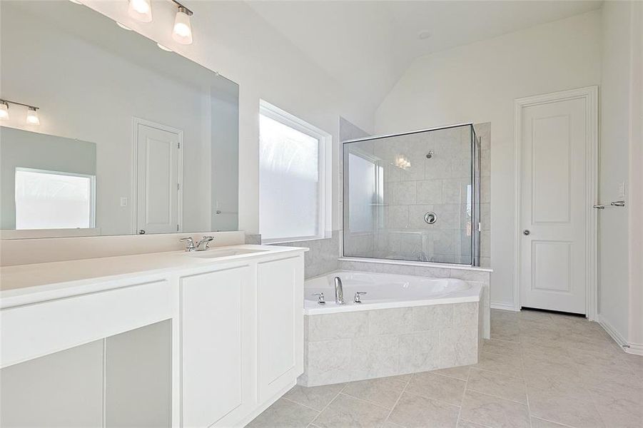 Bathroom with tile patterned flooring, vanity, separate shower and tub, and lofted ceiling