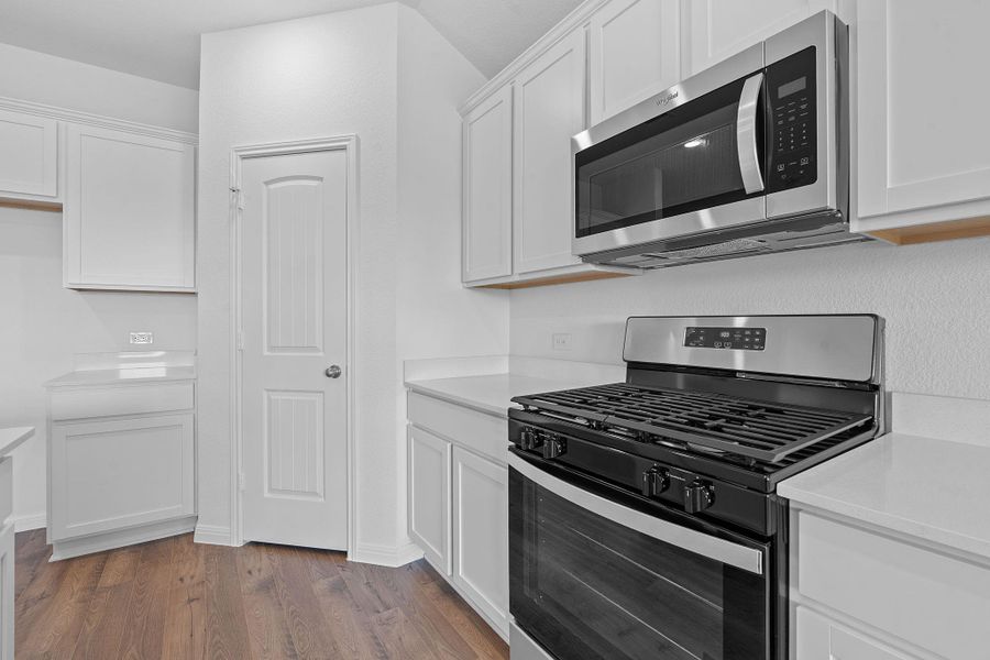 Kitchen featuring stainless steel appliances, dark wood finished floors, white cabinets, and light stone countertops Kitchen featuring stainless steel appliances, dark wood finished floors, white cabinets, and light stone countertops