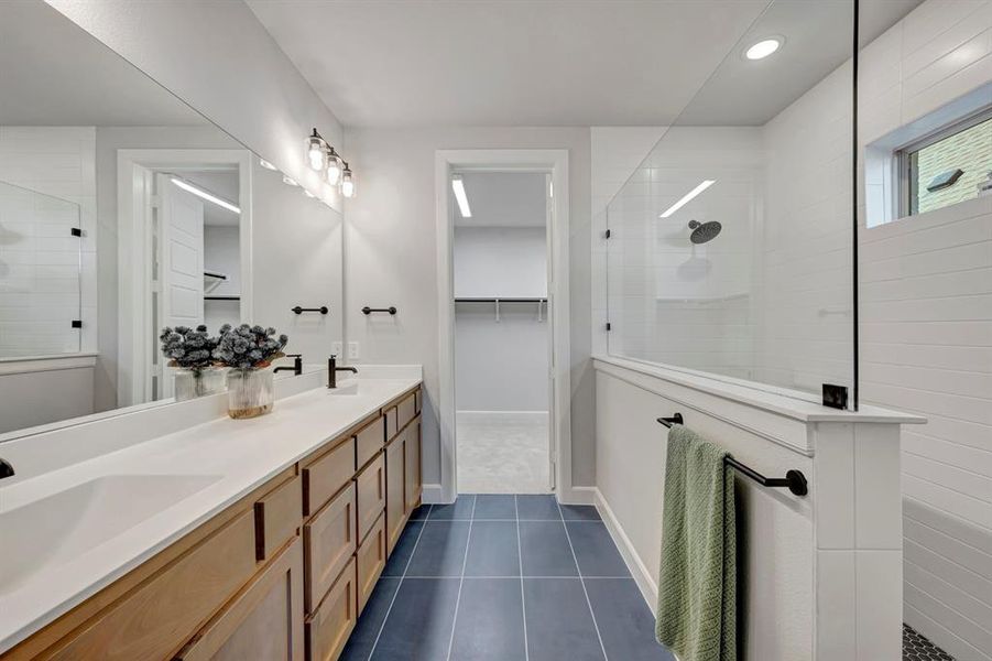 Bathroom with walk in shower, double vanity, a spacious closet, dark tile patterned flooring, and recessed lighting