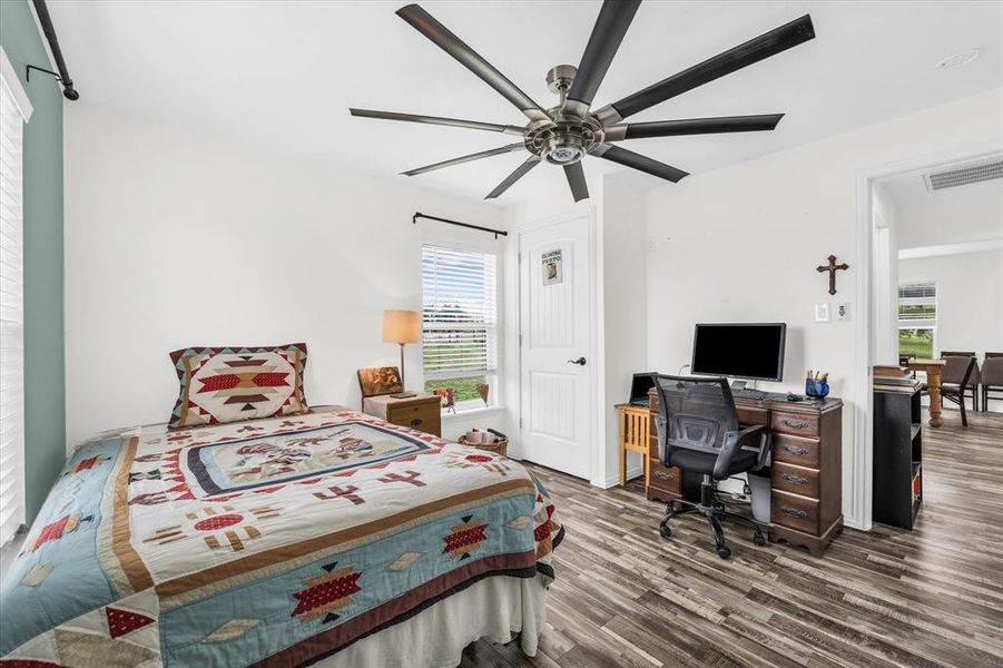 Bedroom featuring dark wood-style floors, ceiling fan, and an office area