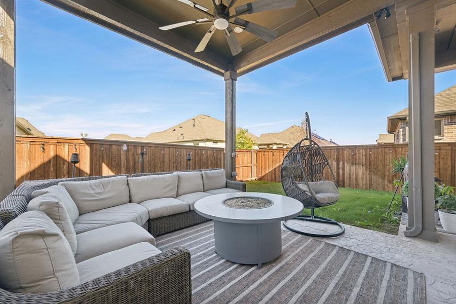 View of patio with ceiling fan and an outdoor living space with a fire pit