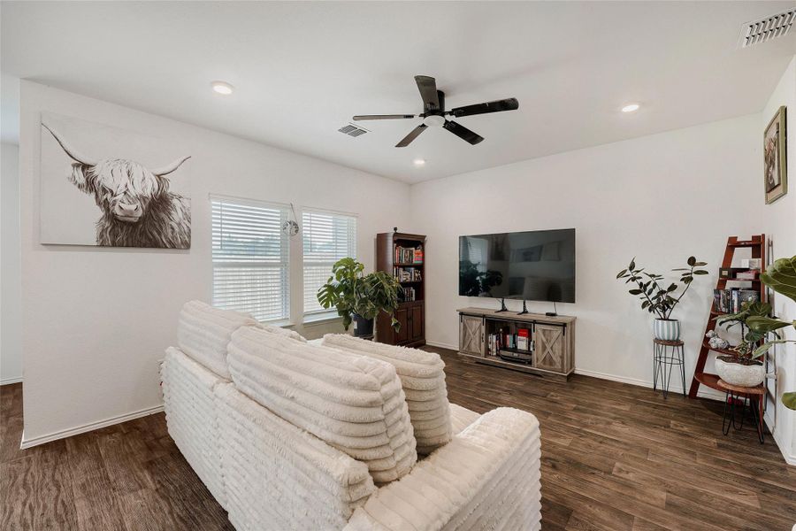 Spacious living area featuring wood-finish flooring, ample natural light from multiple windows, recessed lighting, and a ceiling fan Spacious living area featuring wood-finish flooring, ample natural light from multiple windows, recessed lighting, and a ceiling fan