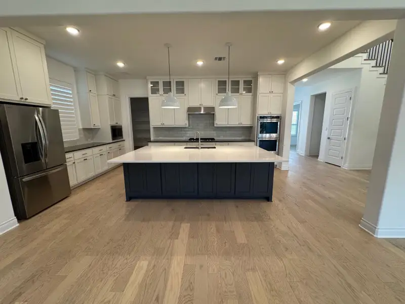 Kitchen featuring stainless steel Kitchen Aid appliances, decorative backsplash, white cabinets, light wood-style flooring, and recessed lighting