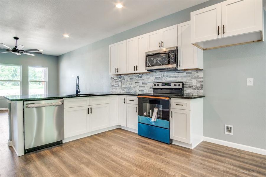 Kitchen with sink, ceiling fan, light wood-type flooring, and stainless steel appliances