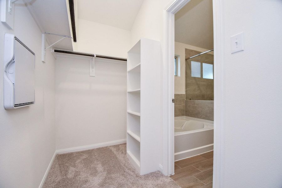 Here is the spacious primary closet that has built-in shelving.
