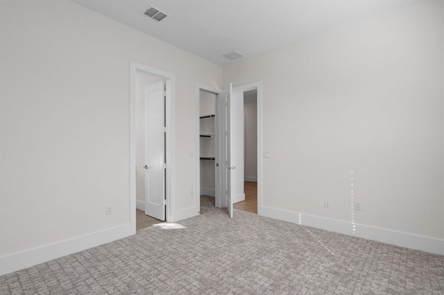 Unfurnished bedroom with a spacious closet and carpet flooring Unfurnished bedroom with a spacious closet and carpet flooring