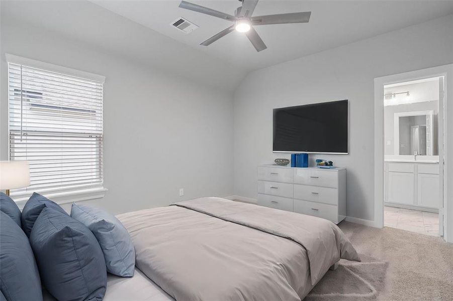 Secondary bedroom features plush carpet, custom paint, ceiling fan with lighting and a large window with privacy blinds, and private access to secondary bathroom.