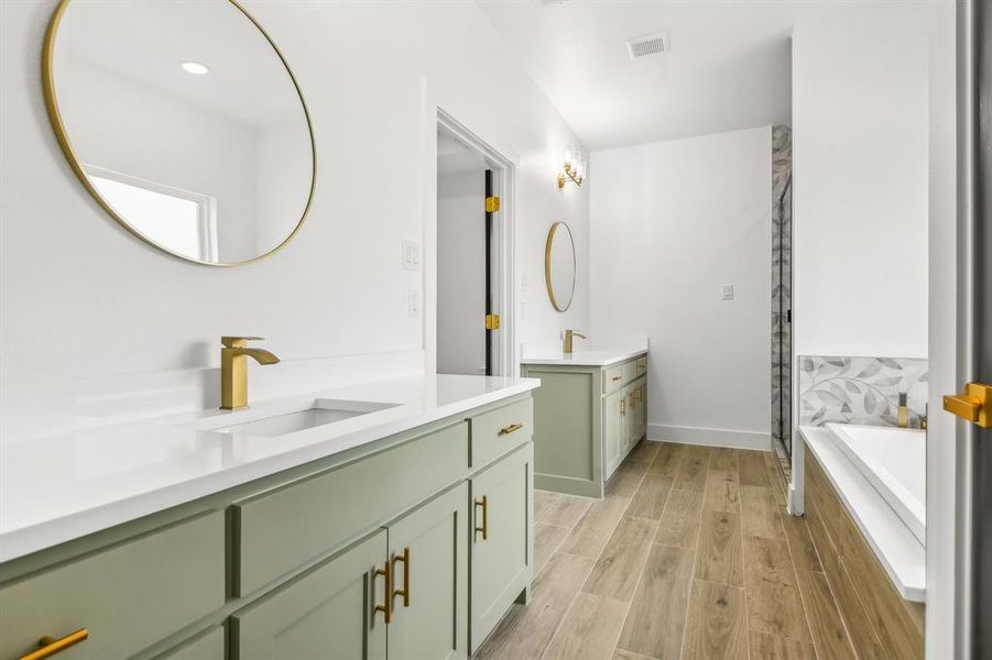 Bathroom featuring two vanities, wood finish floors, a bath, and a shower stall Bathroom featuring two vanities, wood finish floors, a bath, and a shower stall