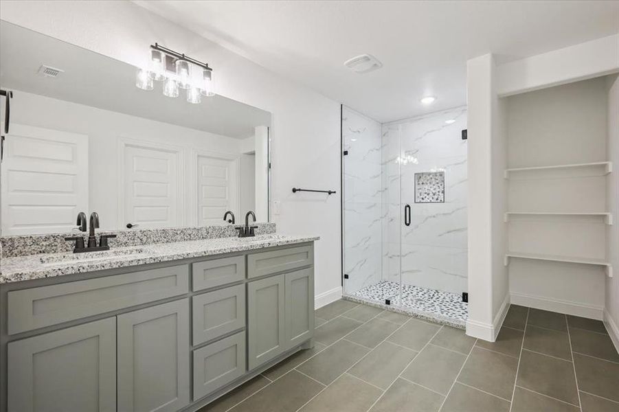 Bathroom featuring a marble finish shower, double vanity, dark tile patterned floors, recessed lighting, and a closet Bathroom featuring a marble finish shower, double vanity, dark tile patterned floors, recessed lighting, and a closet
