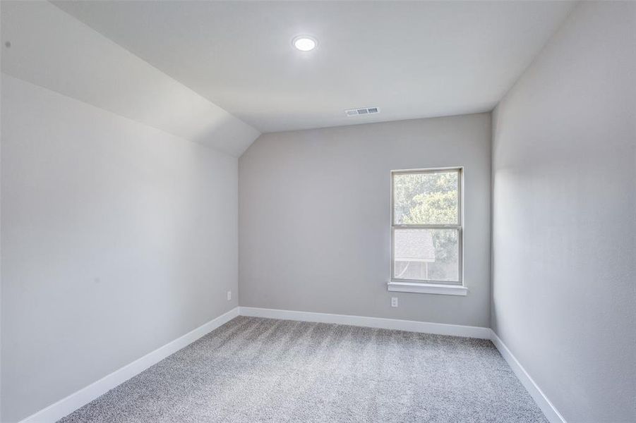 Bedroom with light colored carpet and lofted ceiling