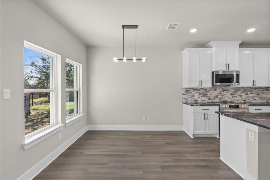 Kitchen with dark wood-type flooring, an inviting chandelier, decorative light fixtures, decorative backsplash, and white cabinets