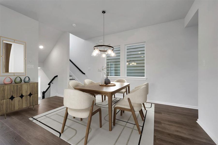 Open-concept dining area featuring wood-finish flooring, a contemporary chandelier, two windows with horizontal blinds, and access to a staircase with dark railings