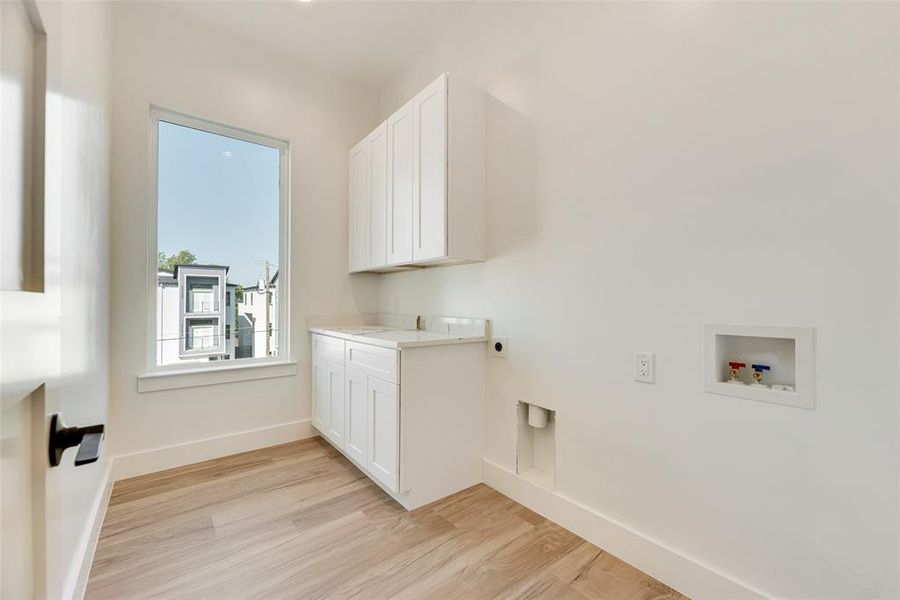 Laundry room featuring light wood-style floors, electric dryer hookup, cabinet space, and hookup for a washing machine Laundry room featuring light wood-style floors, electric dryer hookup, cabinet space, and hookup for a washing machine