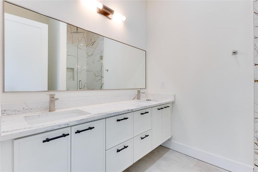 Bathroom with vanity, a shower with shower door, and tile patterned flooring