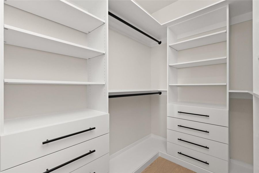Ample custom shelving and integrated drawers maximize storage in this spacious walk-in closet.