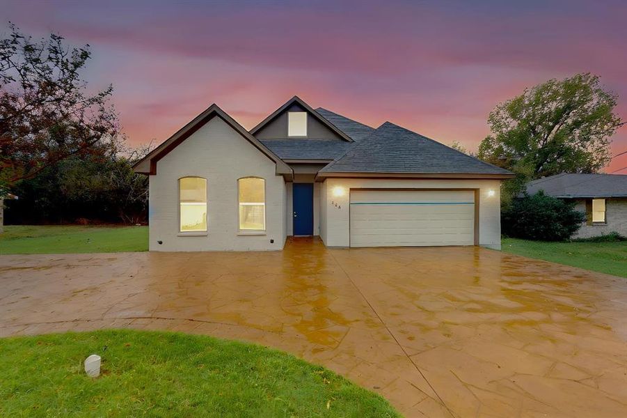 View of front facade with a garage and a lawn