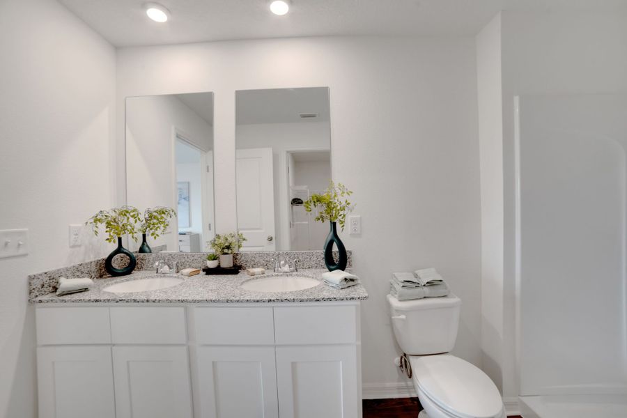 A bathroom with a sink toilet and mirror.