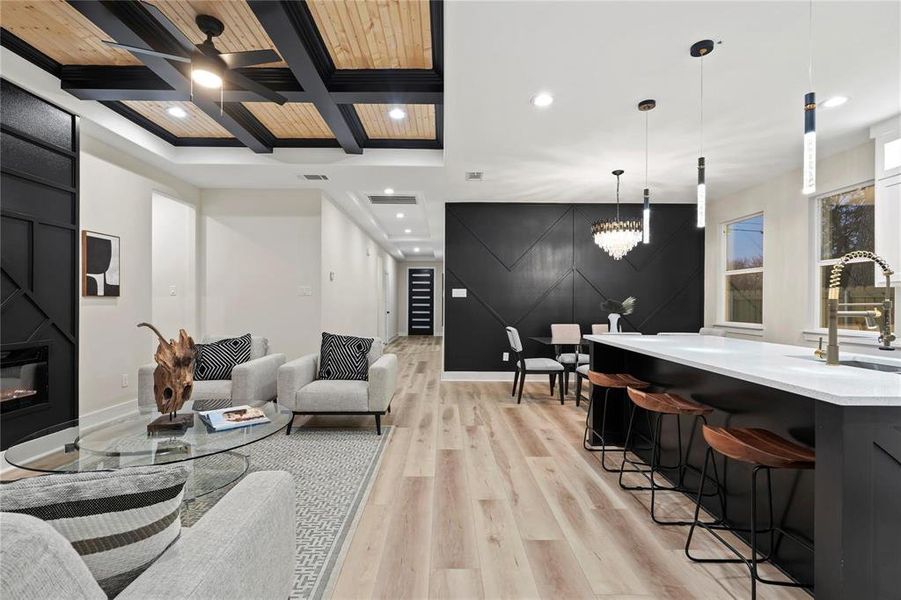 Living area featuring recessed lighting, an accent wall, coffered ceiling, light wood-type flooring, and a glass covered fireplace Living area featuring recessed lighting, an accent wall, coffered ceiling, light wood-type flooring, and a glass covered fireplace