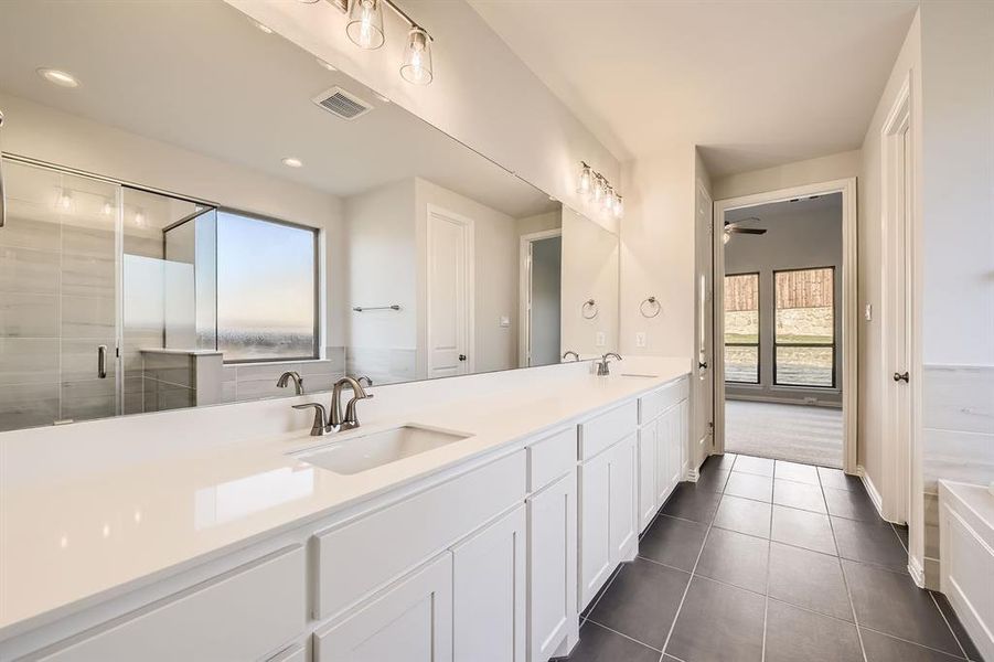 Bathroom featuring tile patterned floors, vanity, and a shower with door