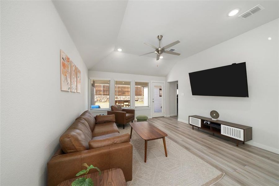 Living room with vaulted ceiling, light hardwood / wood-style flooring, and ceiling fan