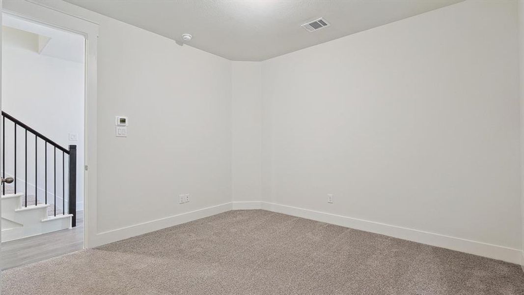 Carpeted room with white walls, white baseboards, and a white ceiling with a single ceiling light fixture