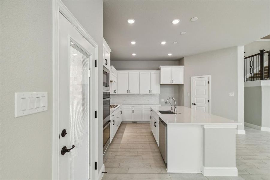 Kitchen with white cabinets, a kitchen island with sink, sink, and tasteful backsplash