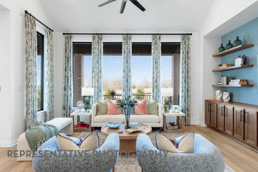 Sitting room featuring vaulted ceiling, ceiling fan, light wood-style floors, and baseboards