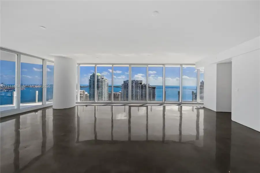 Open-concept interior featuring floor-to-ceiling glass walls, polished concrete flooring, recessed lighting, and a structural column Open-concept interior featuring floor-to-ceiling glass walls, polished concrete flooring, recessed lighting, and a structural column