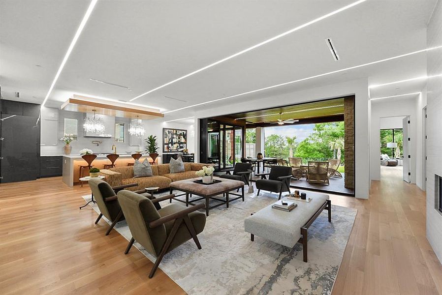 Spacious living area featuring light wood-finish flooring, linear ceiling lighting, and a large multi-panel sliding glass door leading to an outdoor covered patio