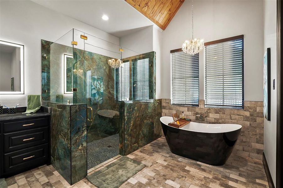 The large walk in shower has granite walls. The porcelain tub has a vaulted ceiling and pretty chandelier.