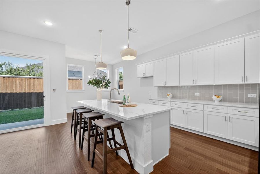 Kitchen with white cabinetry, a kitchen bar, dark wood-style flooring, hanging light fixtures, and recessed lighting