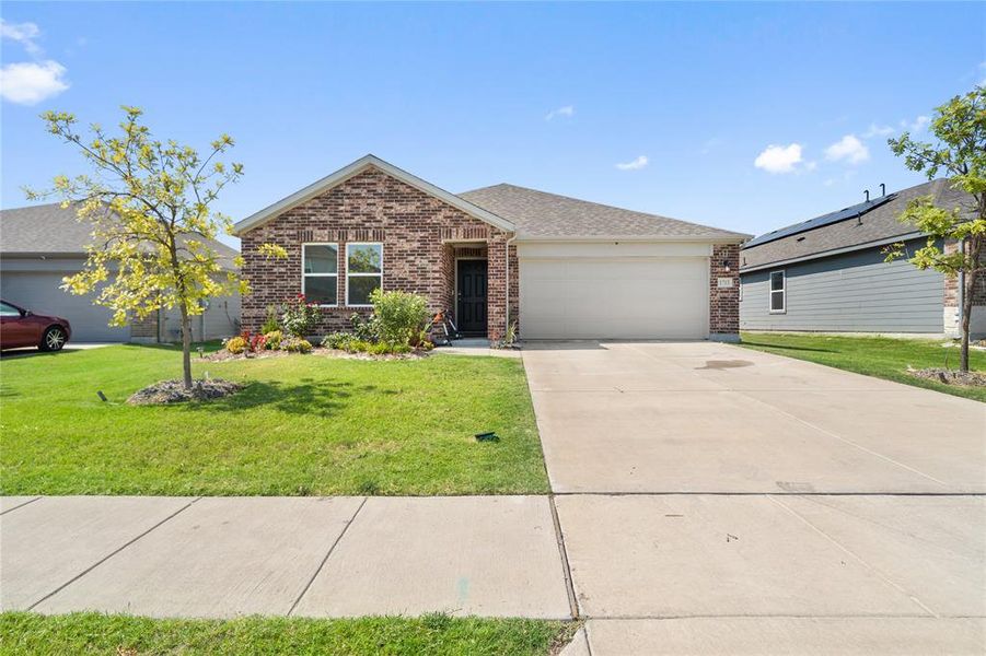 Ranch-style home with brick siding, an attached garage, concrete driveway, and a front lawn