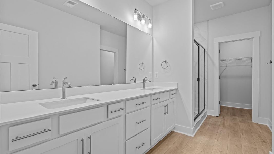 Accomplished design shines in this primary bath with dual vanity and a sleek tiled walk-in shower