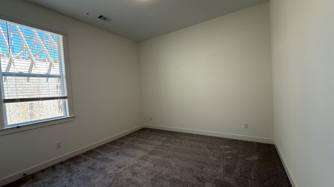 Empty room featuring dark colored carpet and baseboards