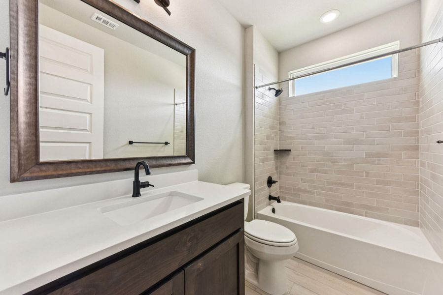 Full bath with washtub / shower combination, vanity, and light wood-type flooring