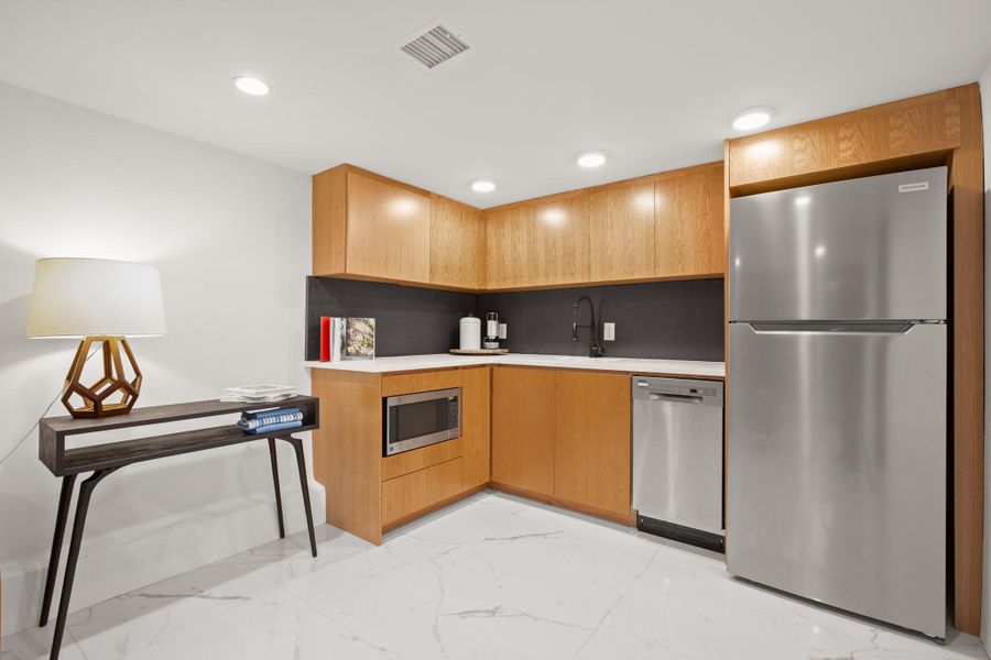 Kitchen with stainless steel appliances, light countertops, light marble finish flooring, and recessed lighting