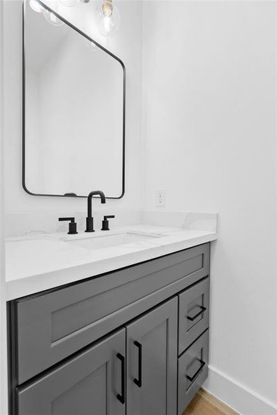 The powder room, thoughtfully positioned next to the staircase, seamlessly maintains the home's design continuity, offering both functionality and aesthetic cohesion throughout.