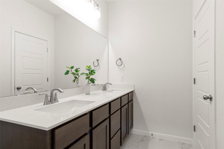 Full bath with double vanity and marble look tile flooring