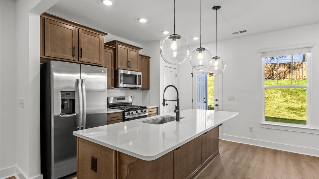 Highly skilled kitchen design includes a 9-foot island, quartz countertops, and stylish pendant fixtures