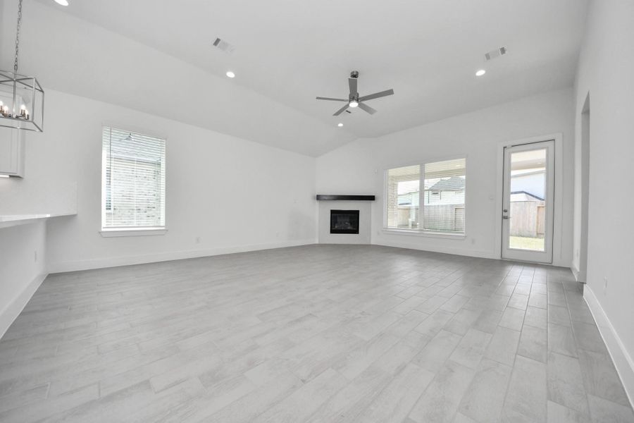 Welcome family and guests to your charming living room! With its high ceilings, recessed lighting, ceiling fan, custom paint, beautiful flooring, and large windows that let in abundant natural light, this room is perfect for gatherings.
